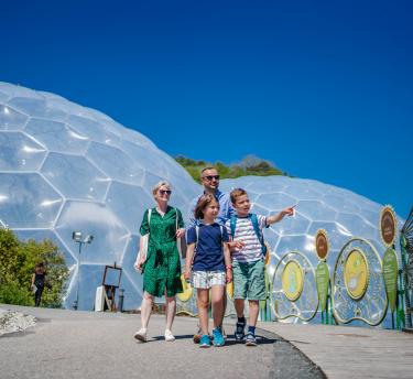 Family walking outside on a sunny day with the biomes in the background